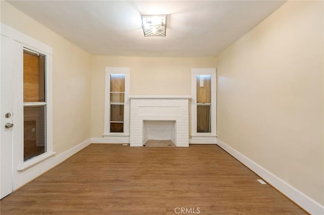 unfurnished living room with a brick fireplace and hardwood / wood-style floors