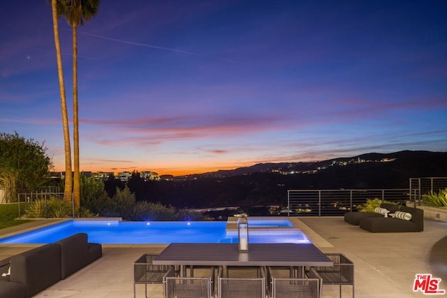 pool at dusk featuring a patio