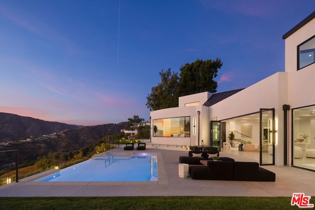 pool at dusk with a mountain view and a patio