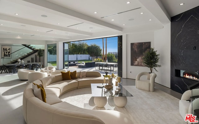 living room featuring a wall of windows, beamed ceiling, and a premium fireplace