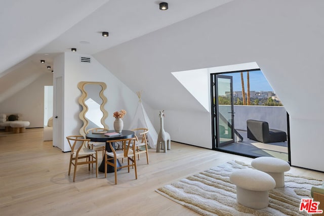 additional living space featuring light wood-type flooring and vaulted ceiling