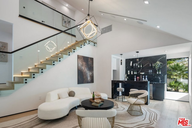 living room featuring bar area, a towering ceiling, and hardwood / wood-style flooring