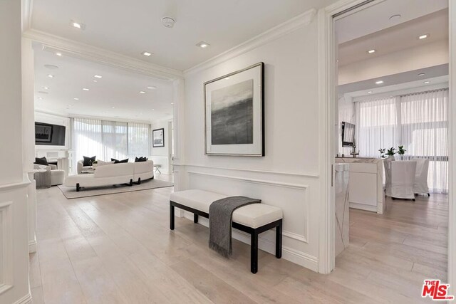 living room with light wood-type flooring, crown molding, and an inviting chandelier