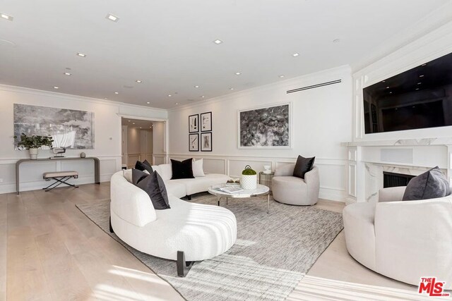 living room with a fireplace, crown molding, and light hardwood / wood-style floors