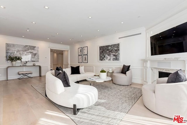 living room with a premium fireplace, ornamental molding, and light hardwood / wood-style floors