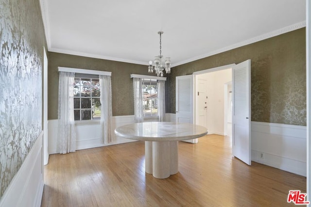 unfurnished dining area with hardwood / wood-style floors, ornamental molding, and a notable chandelier