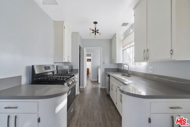 kitchen featuring appliances with stainless steel finishes, white cabinetry, dark hardwood / wood-style flooring, an inviting chandelier, and sink