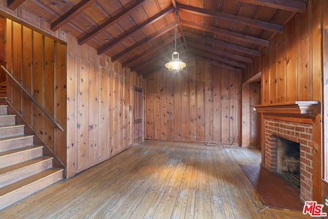 unfurnished living room featuring wooden ceiling, wood-type flooring, vaulted ceiling with beams, and a brick fireplace