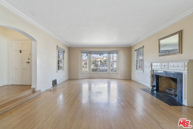 unfurnished living room with a premium fireplace, ornamental molding, and light hardwood / wood-style floors