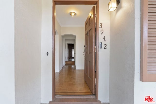 hall with parquet flooring and crown molding