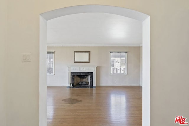 unfurnished living room featuring a fireplace, ornamental molding, and hardwood / wood-style floors