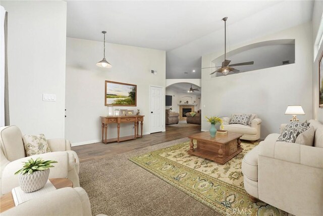 living room featuring ceiling fan, high vaulted ceiling, and hardwood / wood-style flooring