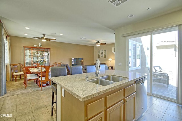 kitchen featuring light tile patterned floors, a kitchen island with sink, light brown cabinetry, stainless steel dishwasher, and sink