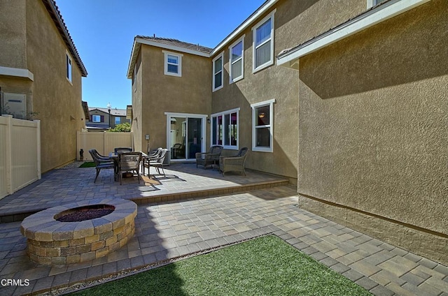 back of house with an outdoor fire pit and a patio