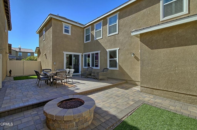 rear view of property featuring an outdoor fire pit and a patio area