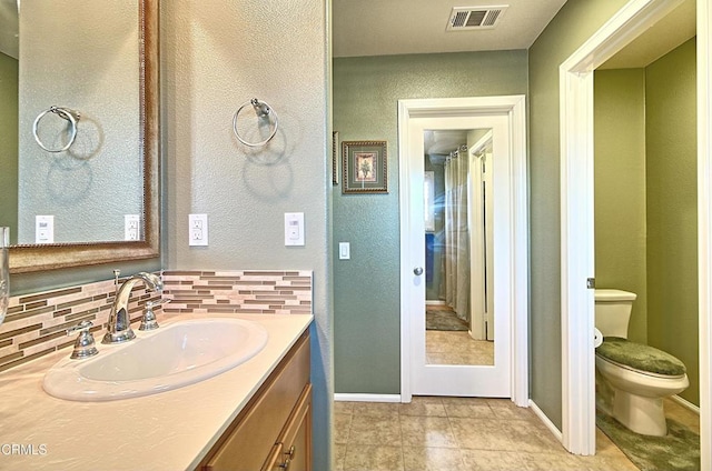 bathroom with toilet, decorative backsplash, and vanity