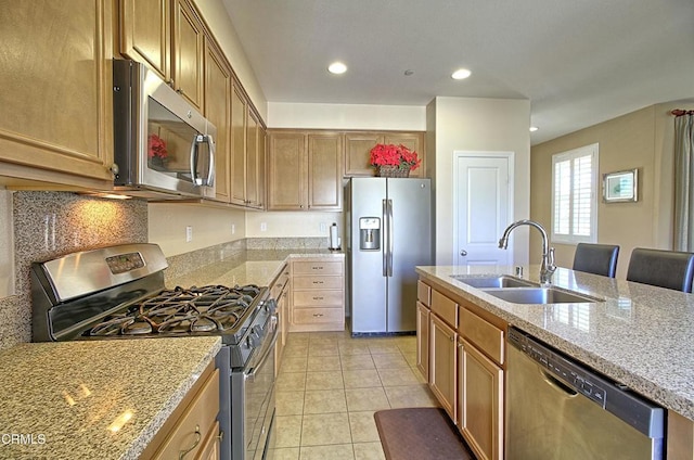 kitchen featuring sink, light stone countertops, appliances with stainless steel finishes, a kitchen breakfast bar, and light tile patterned floors