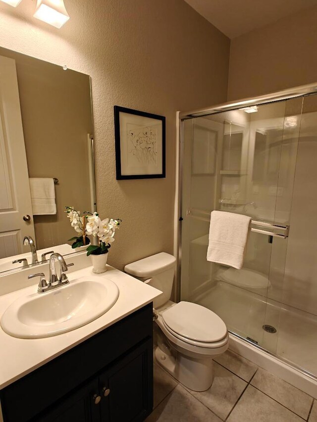 bathroom with an enclosed shower, vanity, tile patterned floors, and toilet