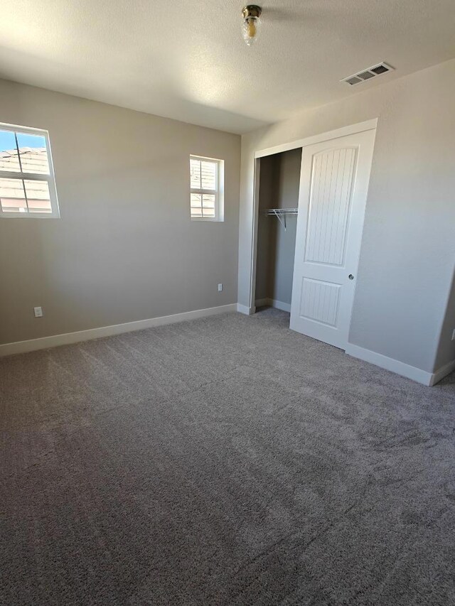 unfurnished bedroom with a closet, a textured ceiling, and carpet