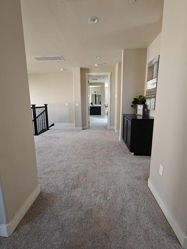 hall featuring carpet floors and a textured ceiling