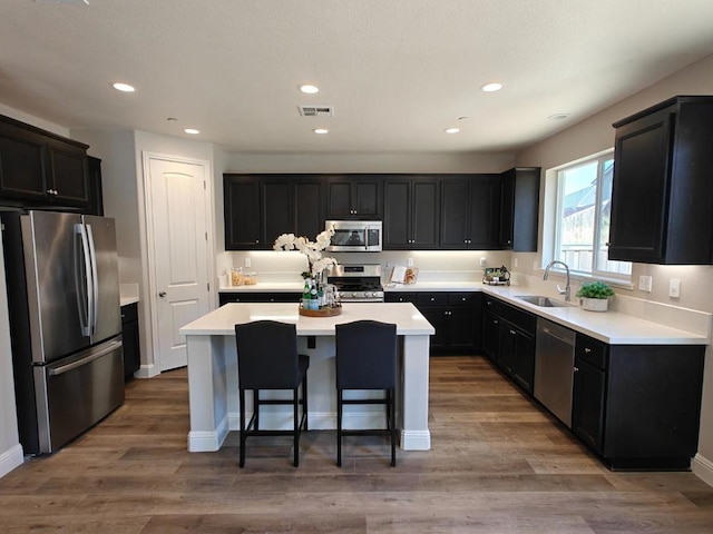 kitchen featuring sink, a breakfast bar area, appliances with stainless steel finishes, a kitchen island, and hardwood / wood-style flooring