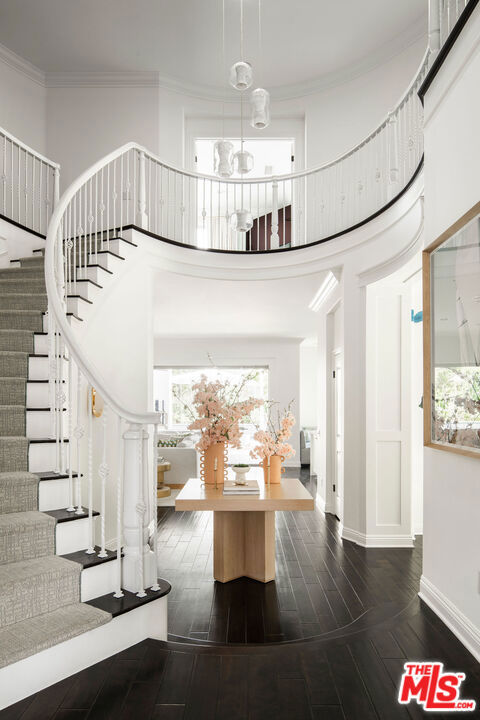 stairway with an inviting chandelier, ornamental molding, a towering ceiling, and hardwood / wood-style flooring