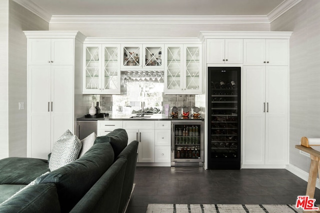 bar with tasteful backsplash, sink, beverage cooler, and white cabinetry