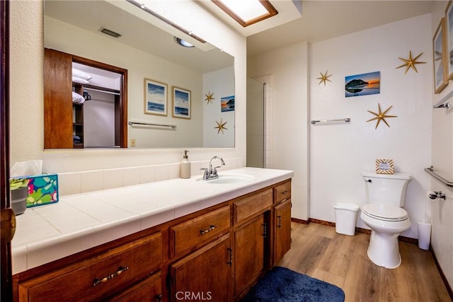 bathroom featuring vanity, toilet, wood finished floors, and visible vents