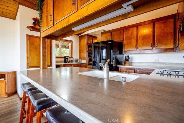 8092 Santa Rosa Rd, Atascadero, CA 93422 - kitchen featuring black refrigerator with ice dispenser, a breakfast bar area, brown cabinets, stovetop, and a sink