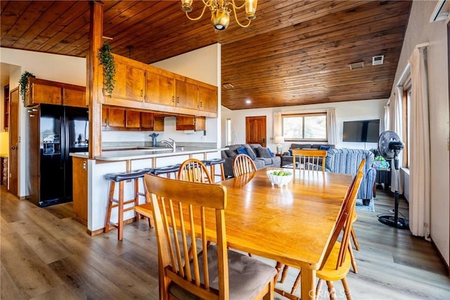 dining area featuring a notable chandelier, wooden ceiling, vaulted ceiling, and light wood-type flooring