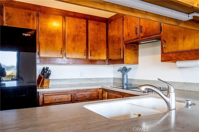 kitchen featuring a sink, brown cabinets, refrigerator, and light countertops