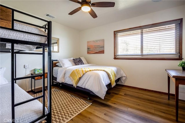 bedroom featuring visible vents, baseboards, ceiling fan, and wood finished floors