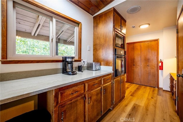 kitchen with light wood-style floors, light countertops, wooden ceiling, lofted ceiling with beams, and black appliances