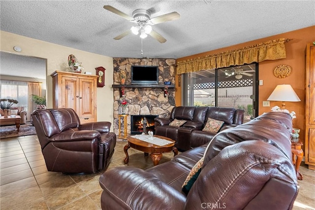 living room with ceiling fan, a stone fireplace, and a textured ceiling