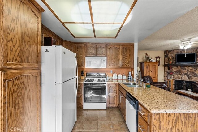 kitchen with ceiling fan, a fireplace, sink, white appliances, and light stone counters