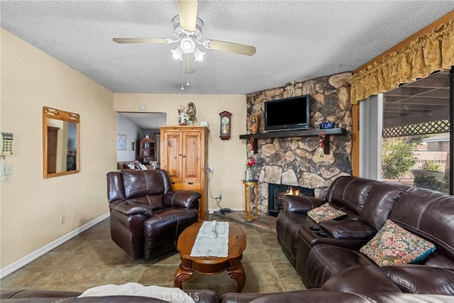 living room featuring ceiling fan, a fireplace, and a textured ceiling