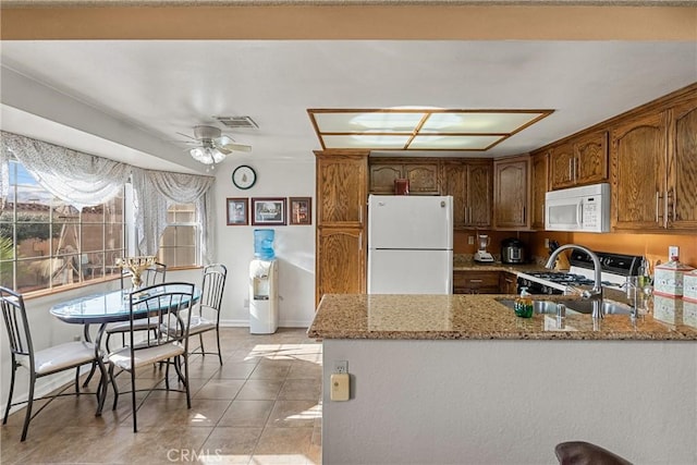 kitchen with white appliances, sink, ceiling fan, light stone counters, and light tile patterned floors