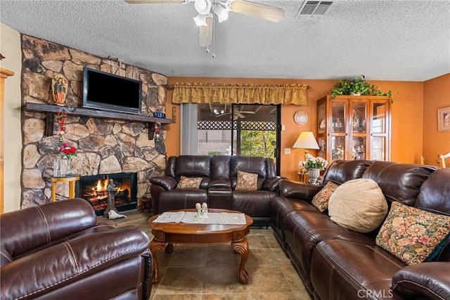 living room with ceiling fan, a textured ceiling, and a fireplace