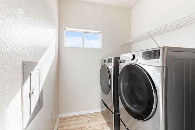 laundry room featuring washing machine and clothes dryer and light hardwood / wood-style floors