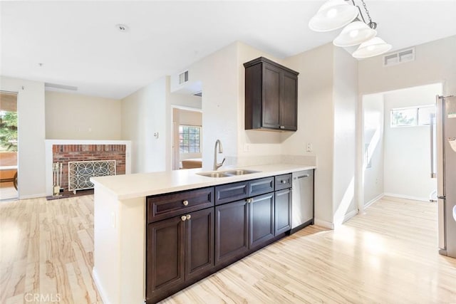 kitchen featuring pendant lighting, dark brown cabinetry, dishwasher, a fireplace, and sink