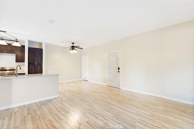 unfurnished living room featuring ceiling fan, light hardwood / wood-style floors, and sink