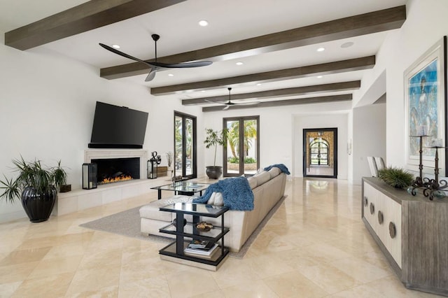 living room with beamed ceiling, a tile fireplace, and ceiling fan