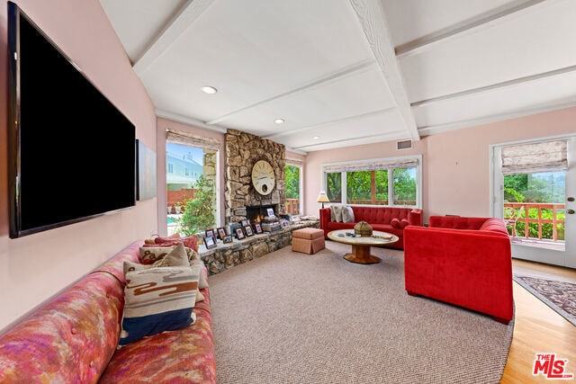 living room featuring a wealth of natural light, beamed ceiling, and a fireplace