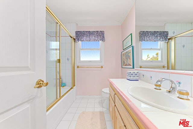 full bathroom featuring shower / bath combination with glass door, tile patterned flooring, vanity, toilet, and crown molding