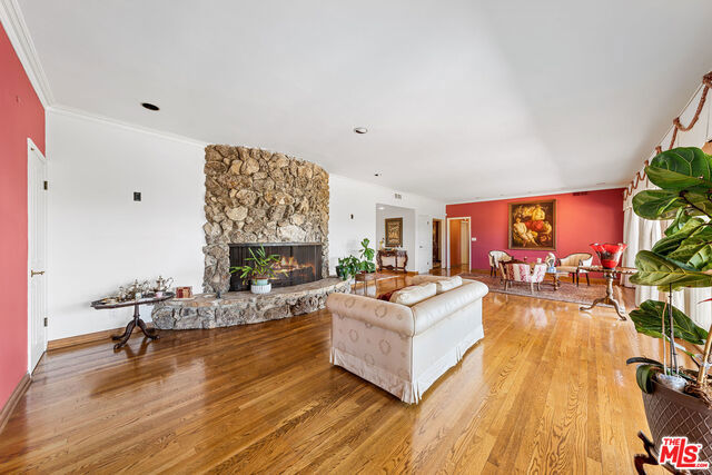 living room with wood-type flooring, a fireplace, and crown molding