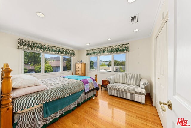 bedroom with ornamental molding and wood-type flooring