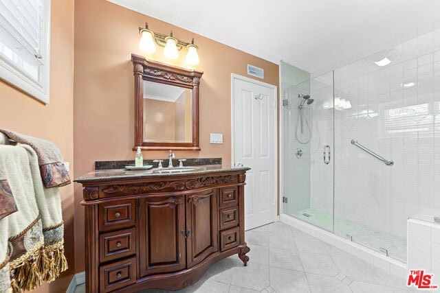 bathroom featuring a shower with shower door, vanity, and tile patterned flooring