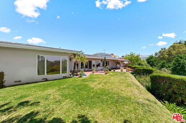 rear view of property with a lawn and a patio