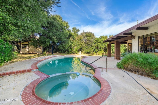 view of pool featuring an in ground hot tub and a storage shed