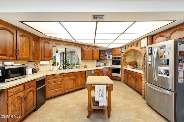 kitchen with decorative backsplash, sink, stainless steel appliances, and a kitchen island